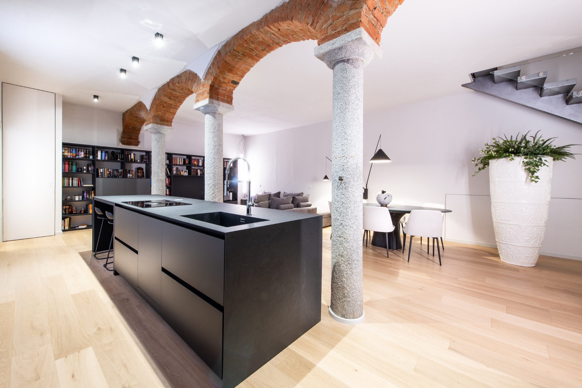 Cucina nera con isola sotto gli archi in mattoni