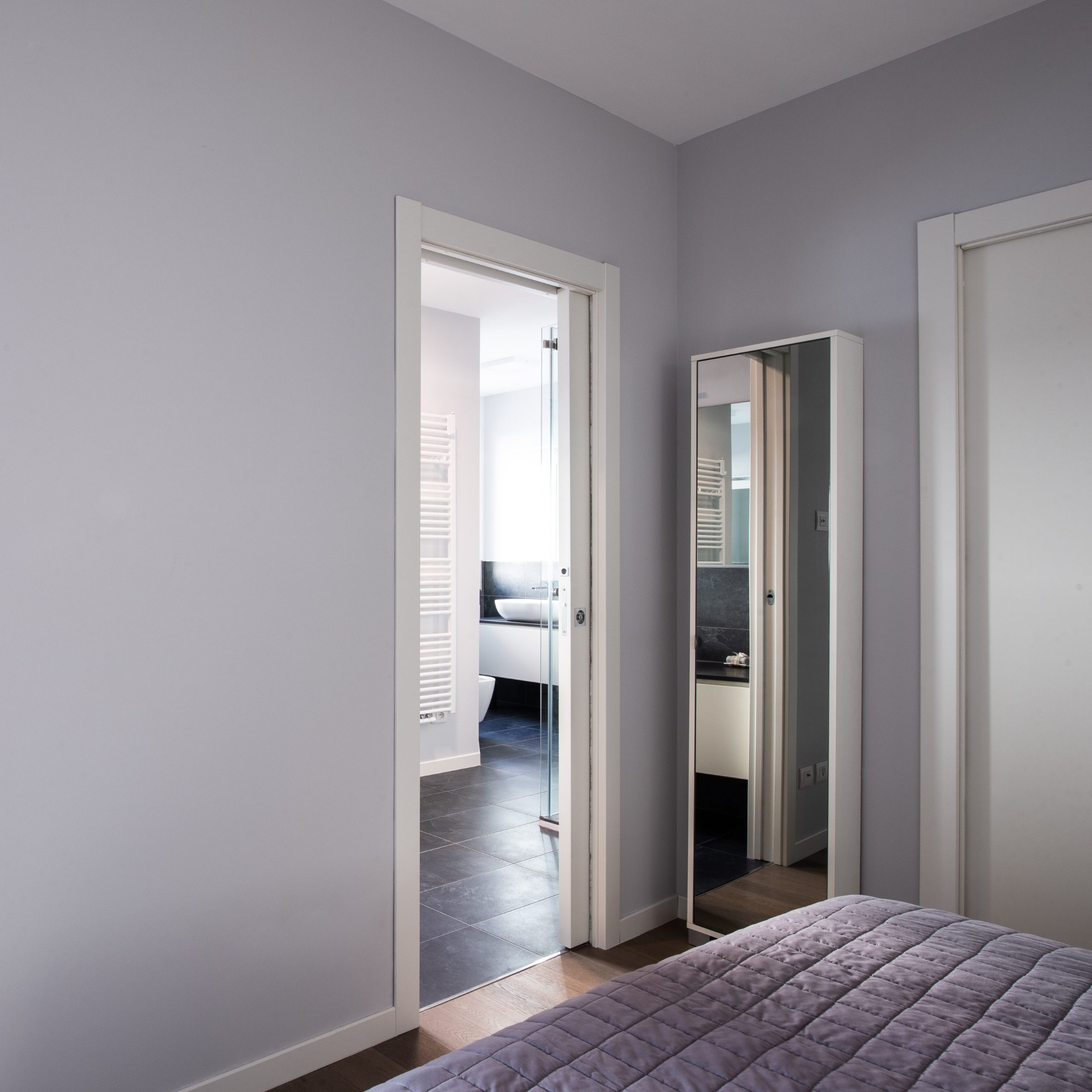 Passaggio tra camera da letto e bagno padronale con pareti grigio chiaro