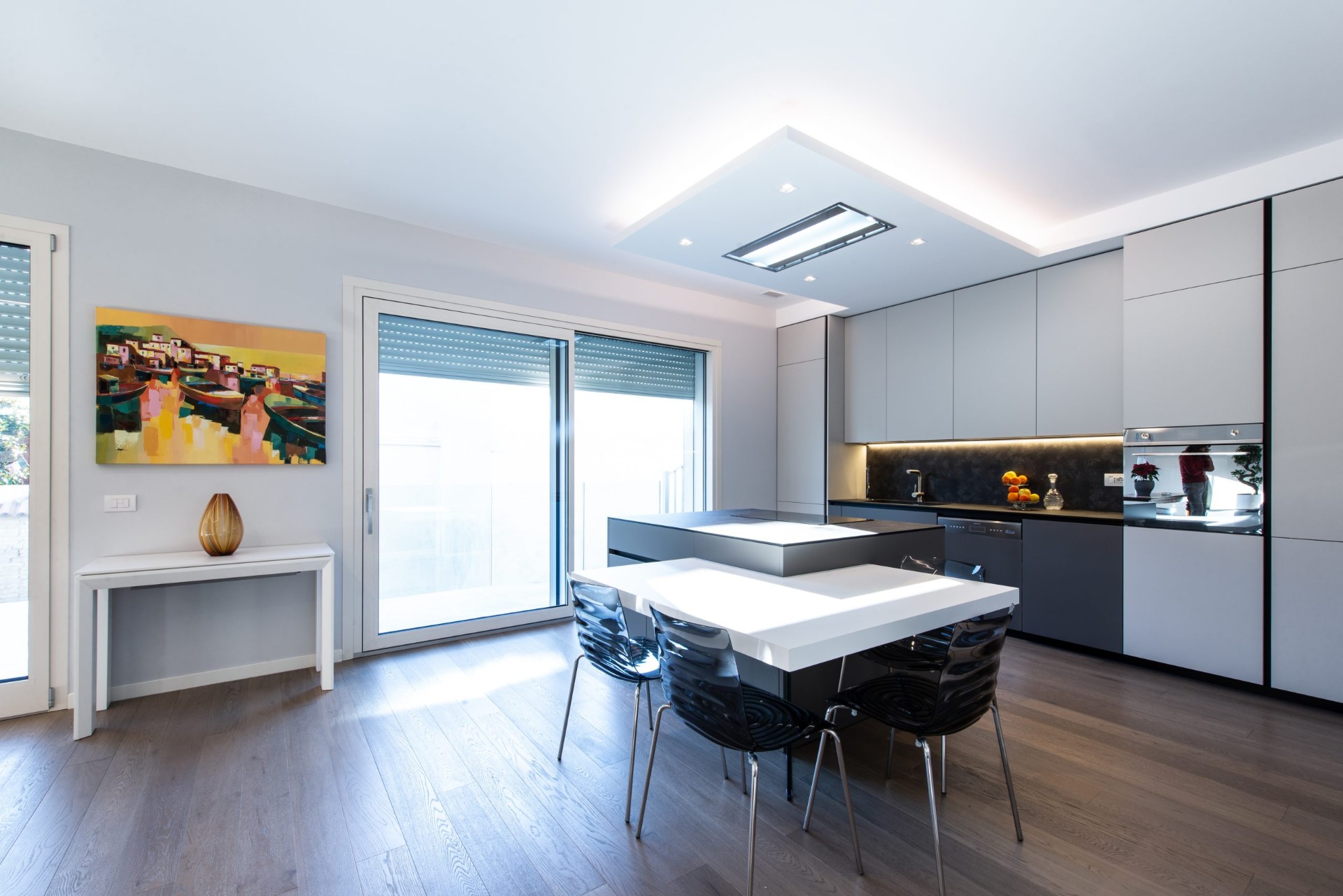 Cucina con isola, tavolo bianco e ampia vetrata sul terrazzo