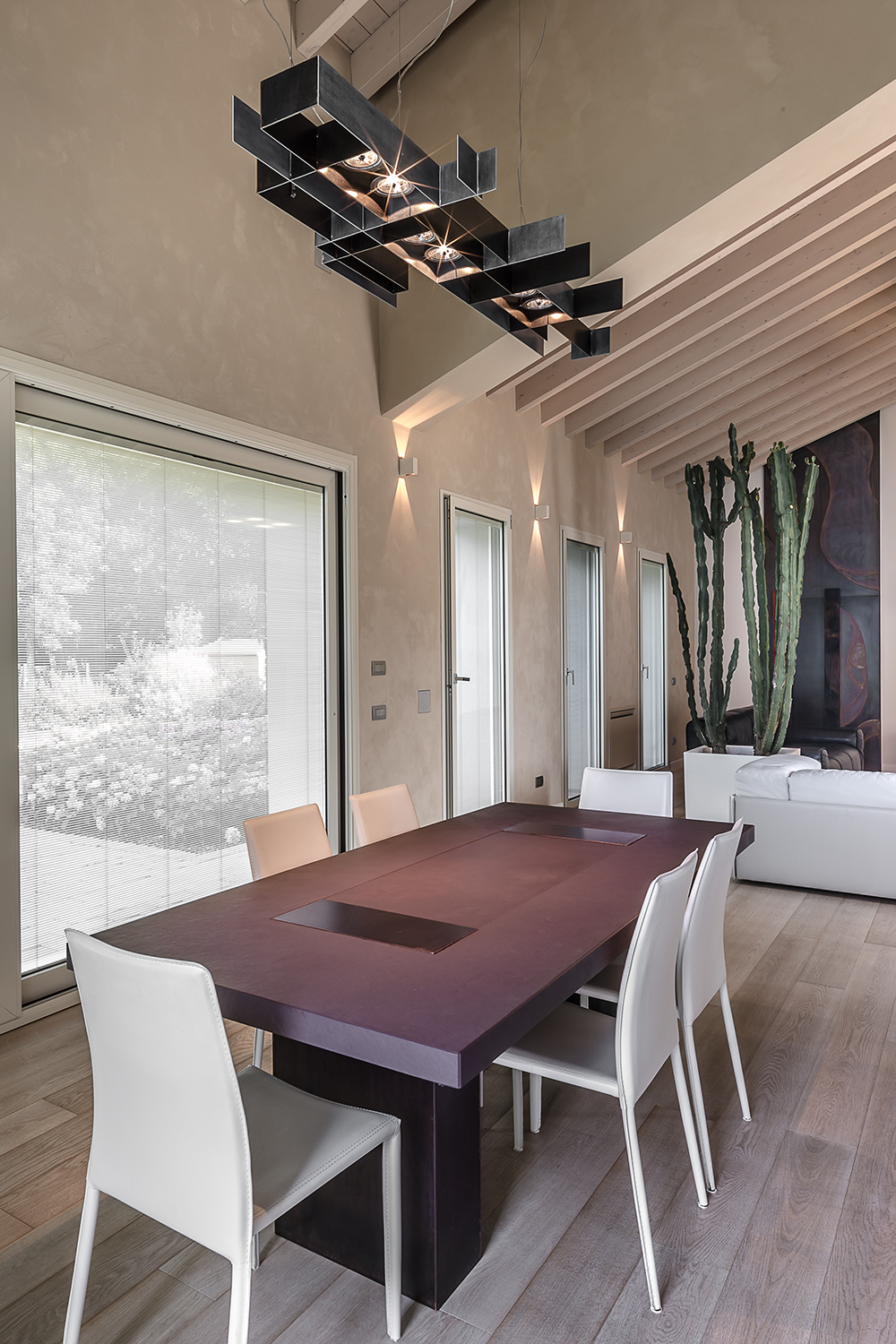 Sala da pranzo con tavolo materico e ampia vetrata sul giardino
