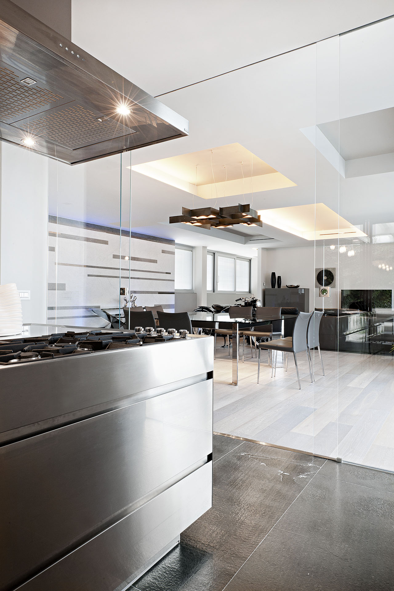 Cucina in acciaio con parete vetrata verso la zona pranzo