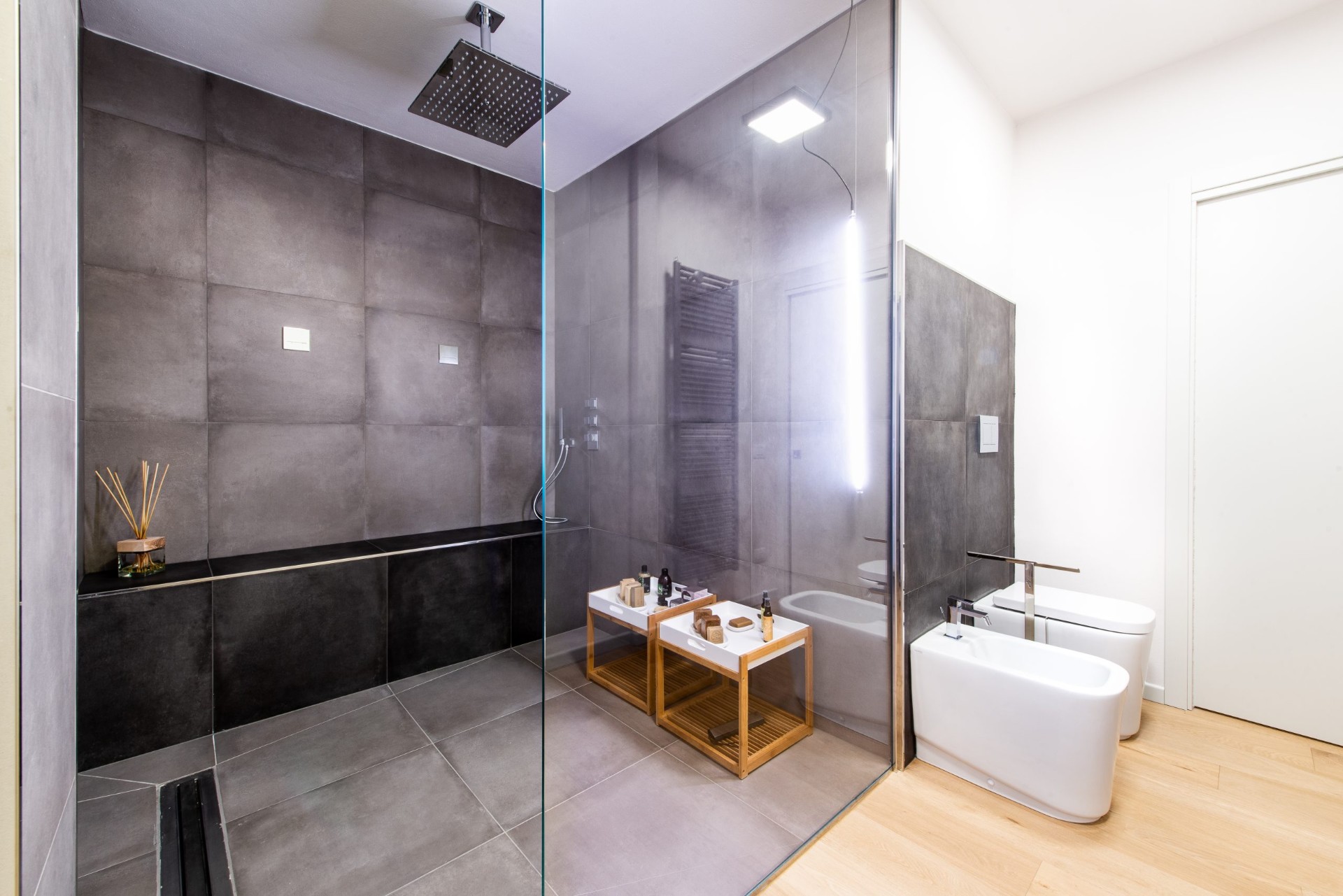 Bagno padronale con doccia walk-in e rivestimenti scuri