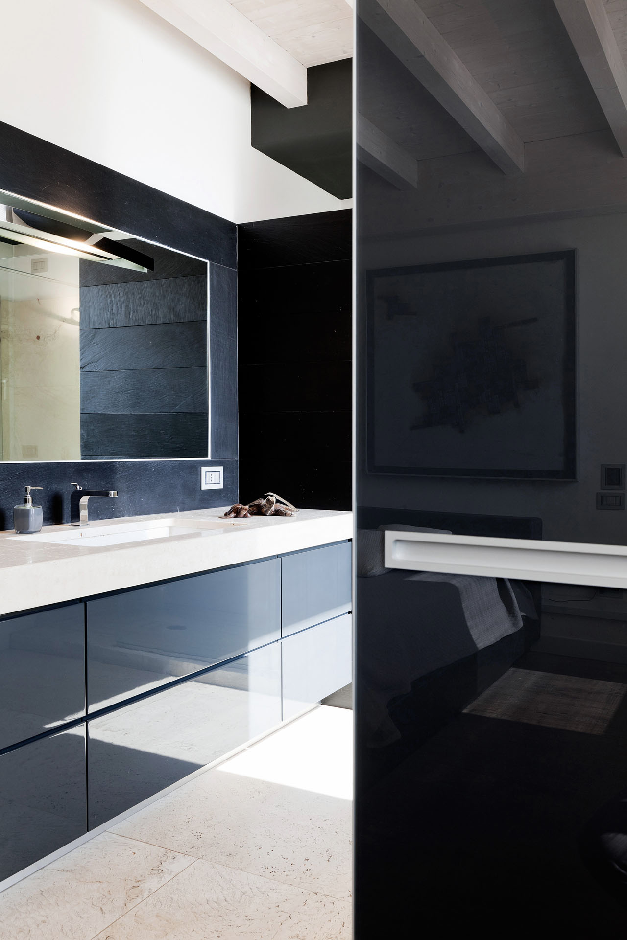 Bagno padronale con rivestimenti scuri e mobile in laccato lucido